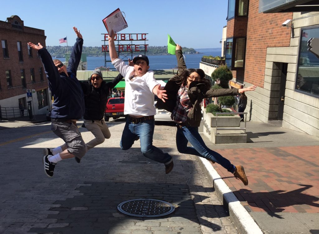 Team players in Seattle taking a group photo jumping by Pike Place Market as part of a corporate scavenger hunt.