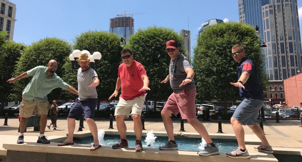 Players pose on a fountain during a team building scavenger hunt in Nashville