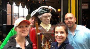 Players on a Boston scavenger hunt on the Freedom Trail pose with a sculpture of a colonial soldier.