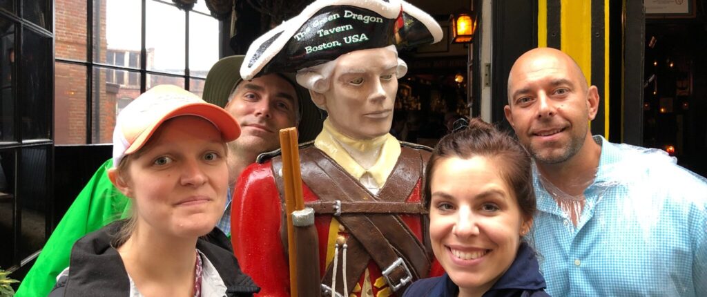 Players on a Boston scavenger hunt on the Freedom Trail pose with a sculpture of a colonial soldier.