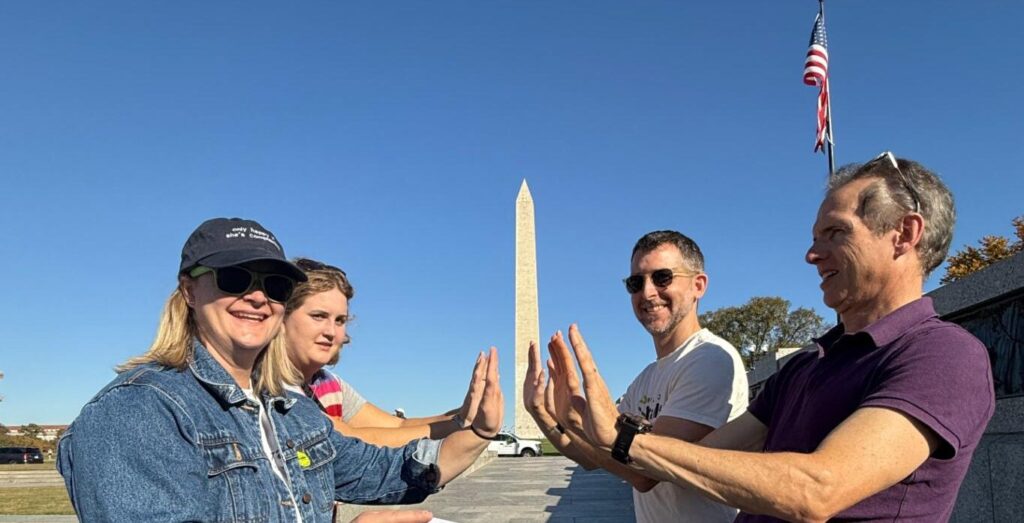 A team on a scavenger hunt on the National Mall, posing with the Washington Monument
